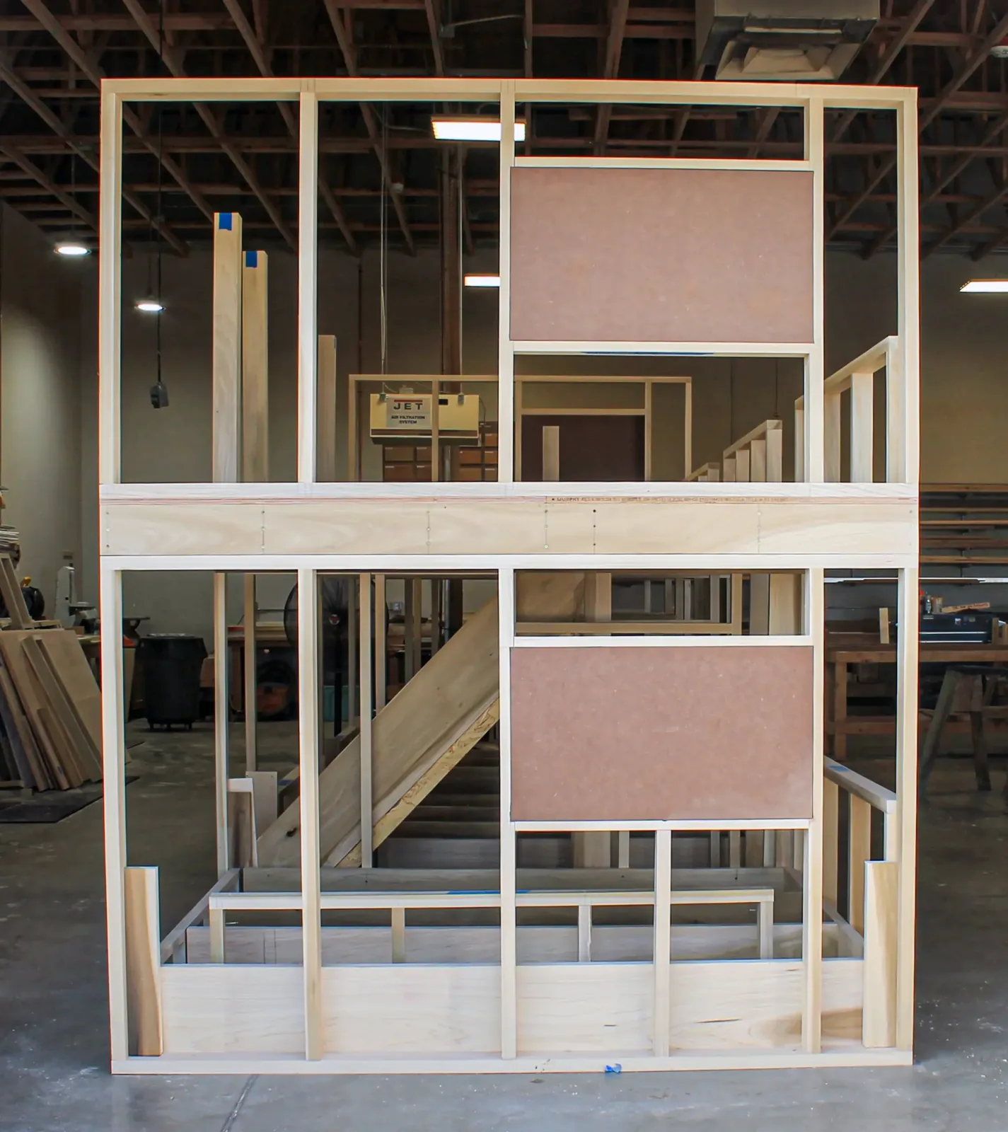 Full-height framed wall assembly with stair and panel openings, built in the shop
