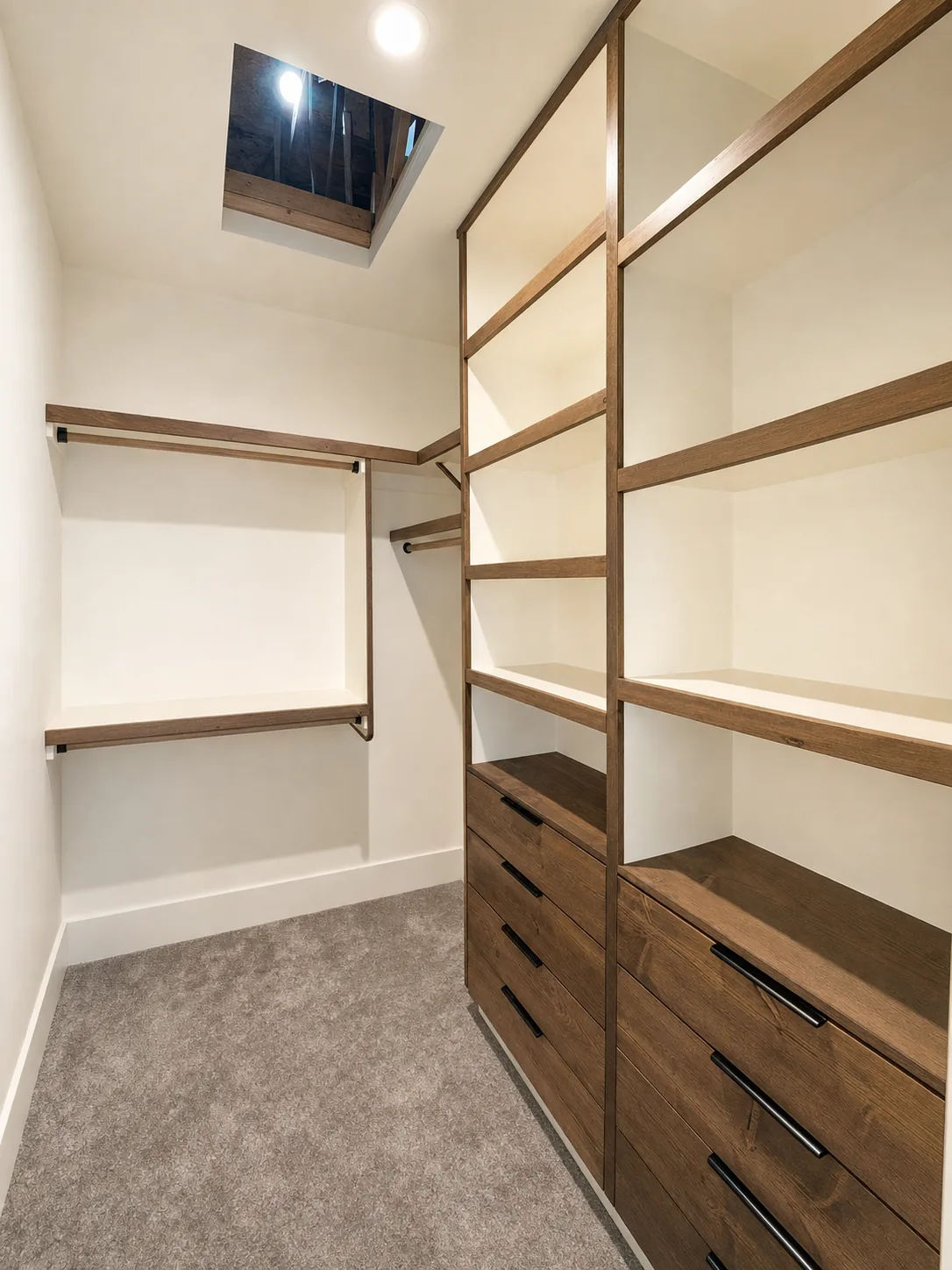 Walk-in closet built-in with open shelving, drawer banks, and hanging rods