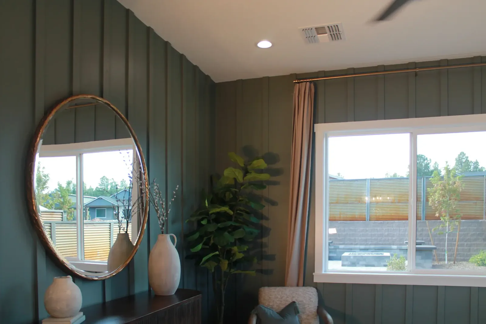 Green board and batten wall with a round mirror above a console and a white-cased window
