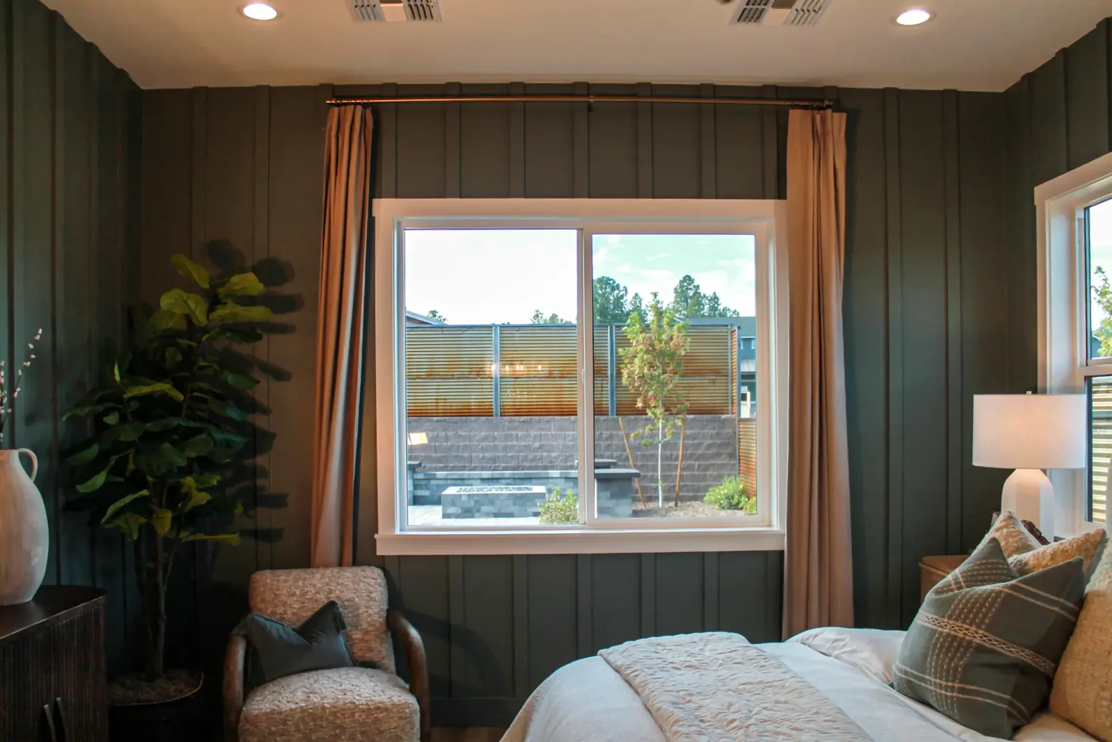 Green board and batten bedroom wall wrapping a white-cased window with curtains
