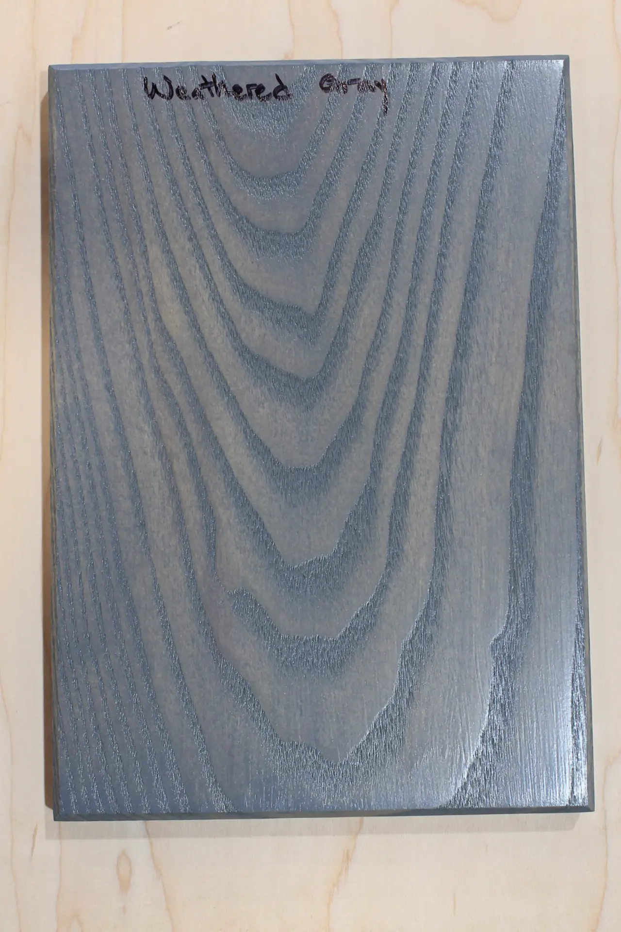 Finish sample board in an even blue-gray stain, hand labeled "Weathered Gray"