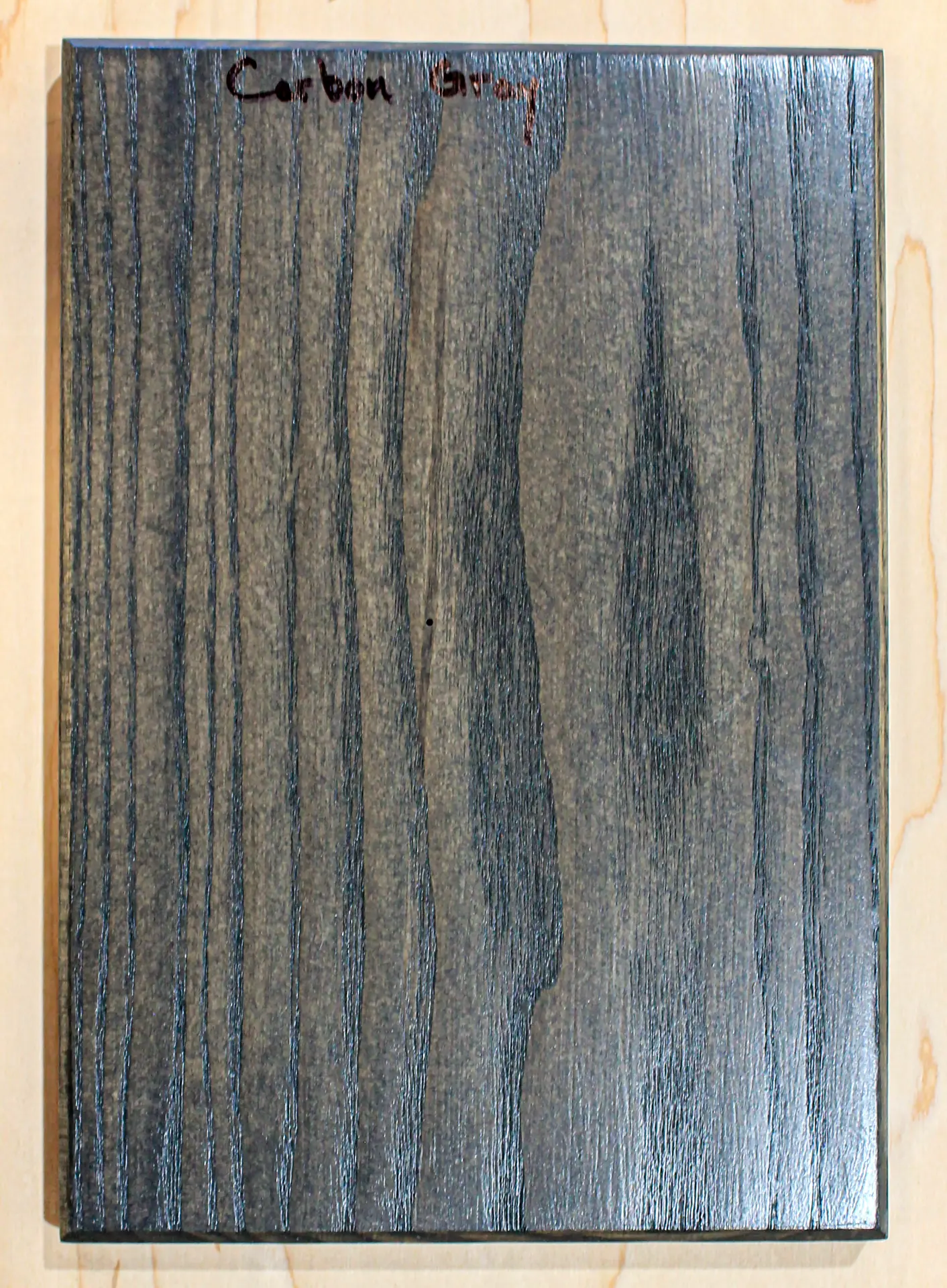 Finish sample board in a dark charcoal-gray stain, hand labeled "Carbon Gray"