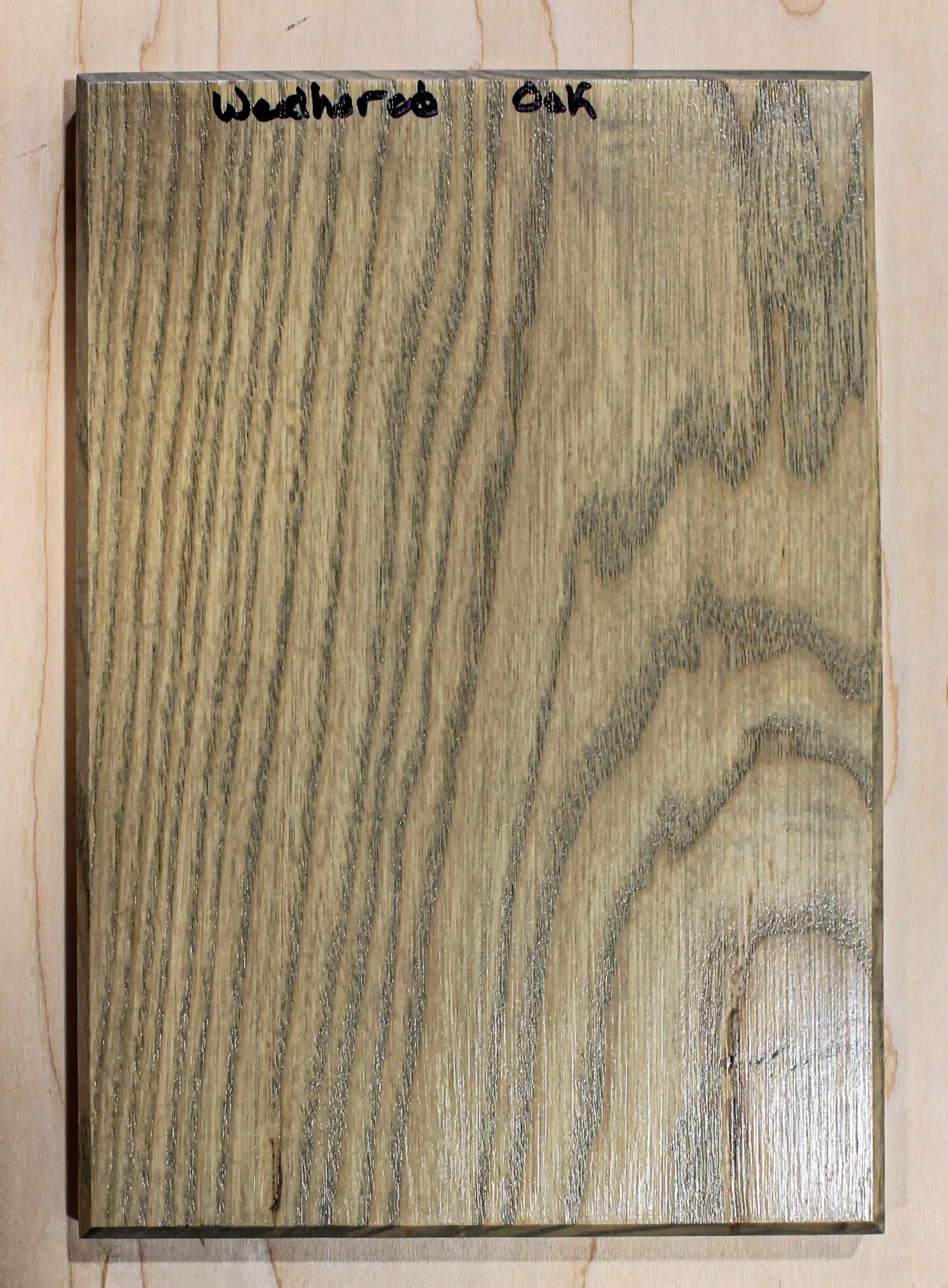 Finish sample board in a soft gray-tan stain over open grain, hand labeled "Weathered Oak"