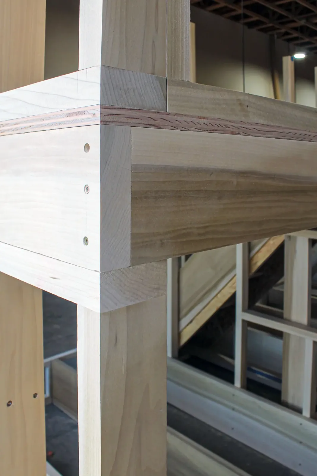 Close-up of a wood post and beam joint with a reeded detail band and exposed screws