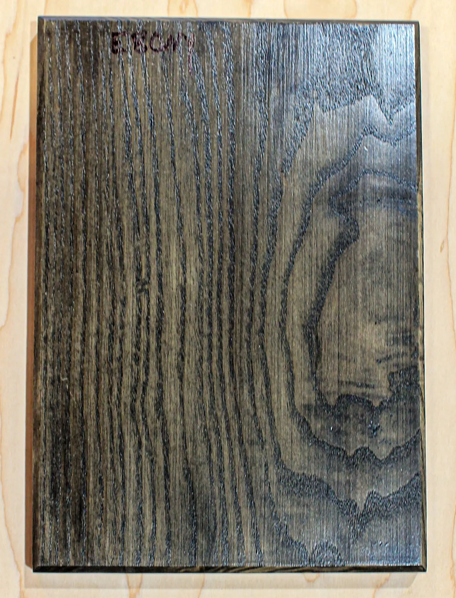 Finish sample board in a deep near-black stain, hand labeled "Ebony"