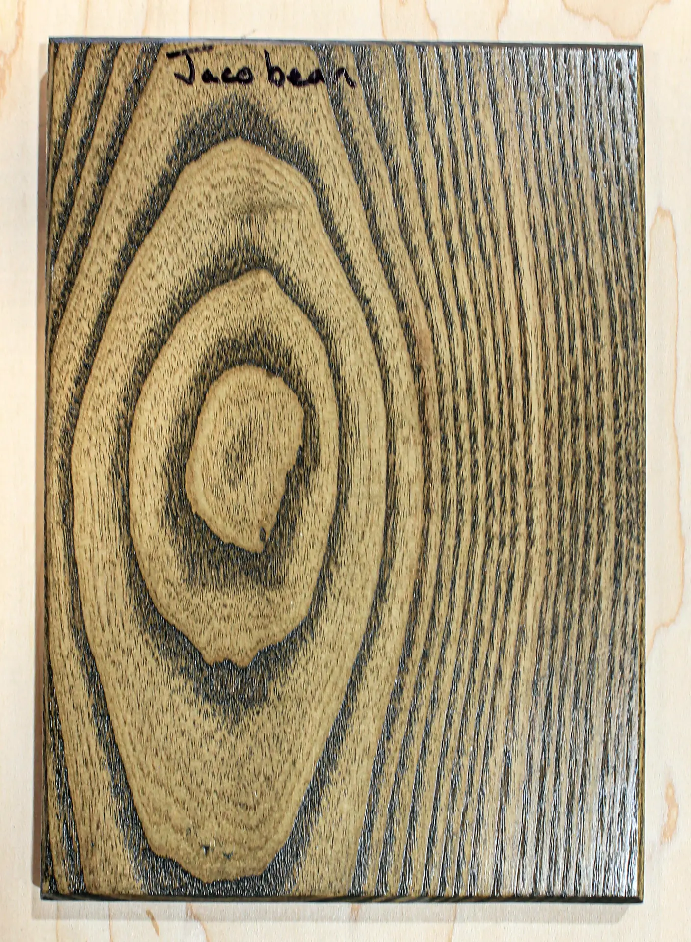 Finish sample board in a warm brown stain with near-black grain, hand labeled "Jacobean"