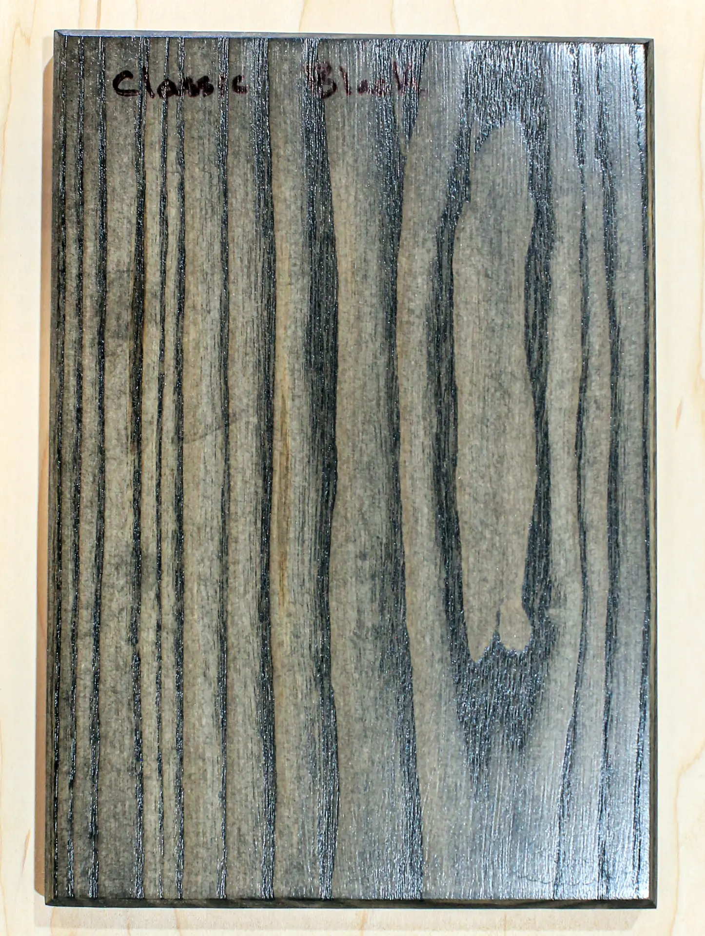 Finish sample board in a translucent black stain that still shows the grain, hand labeled "Classic Black"