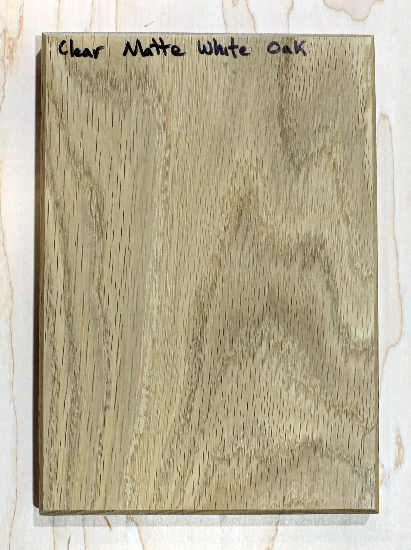 Finish sample board with a flat clear topcoat over open grain, hand labeled "Clear Matte White Oak"