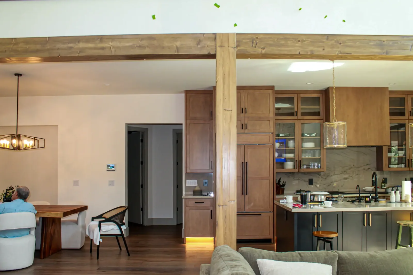 Open living and kitchen area with stained ceiling beams and a wrapped wood column
