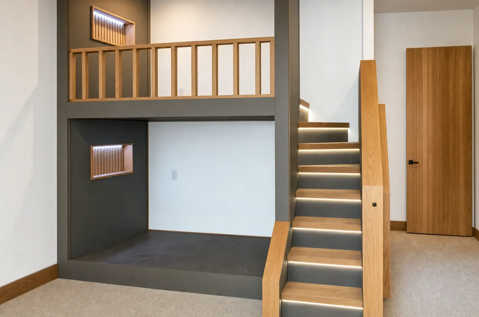 Built-in bunk unit with a wood railing, lit stair treads, and recessed lit niches beside a wood door
