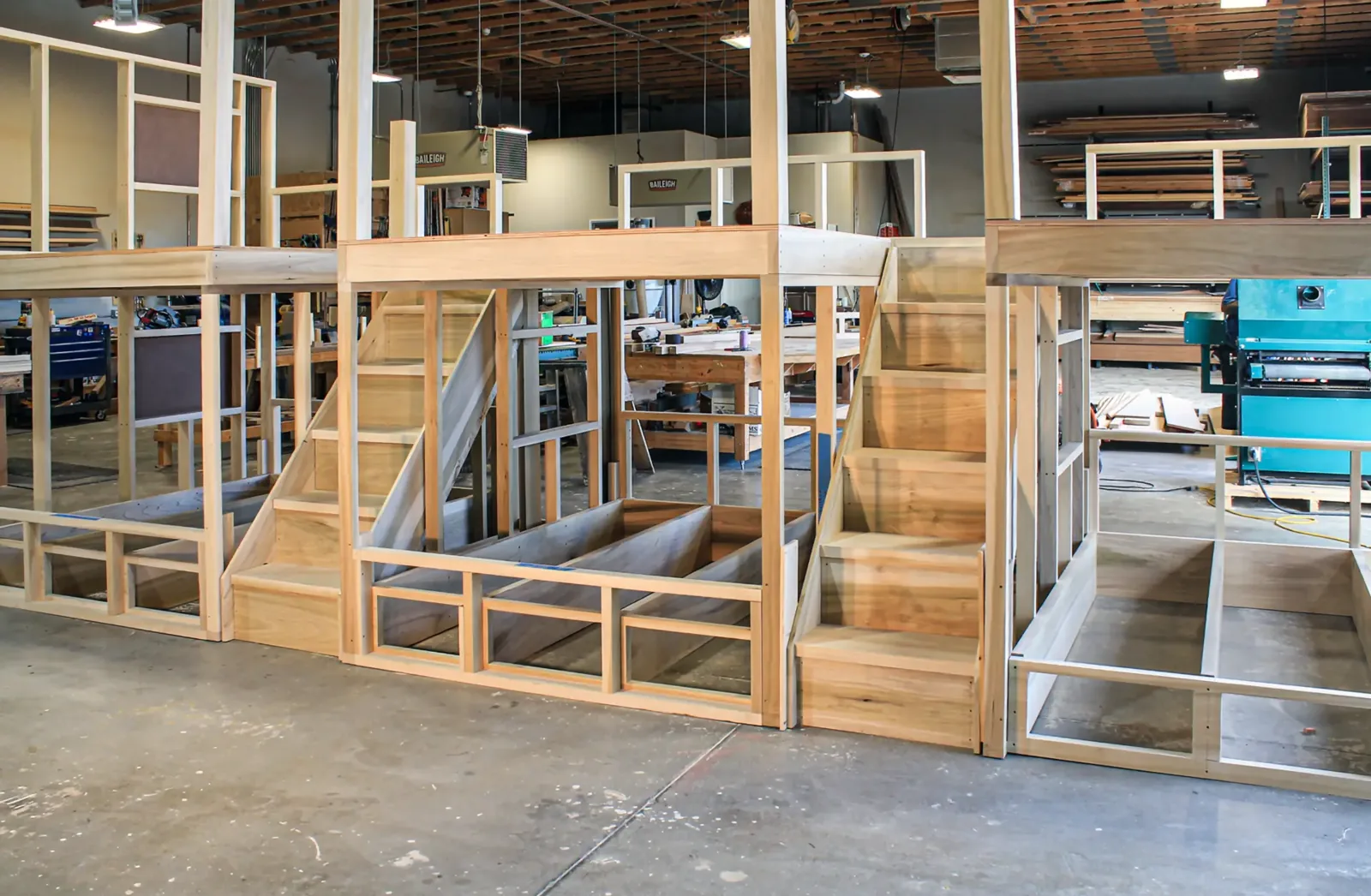 Wide shop view of stair, railing, and framed wall assemblies standing on the floor